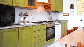 A kitchen with green cabinets, a stove, a dishwasher, and a wooden dining table. - BNBOOK BORROMEO 1 RHO (RHO)