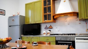 A kitchen with green cabinets, a black microwave, a gas stove, and a dining table with chairs. - BNBOOK BORROMEO 1 RHO (RHO)