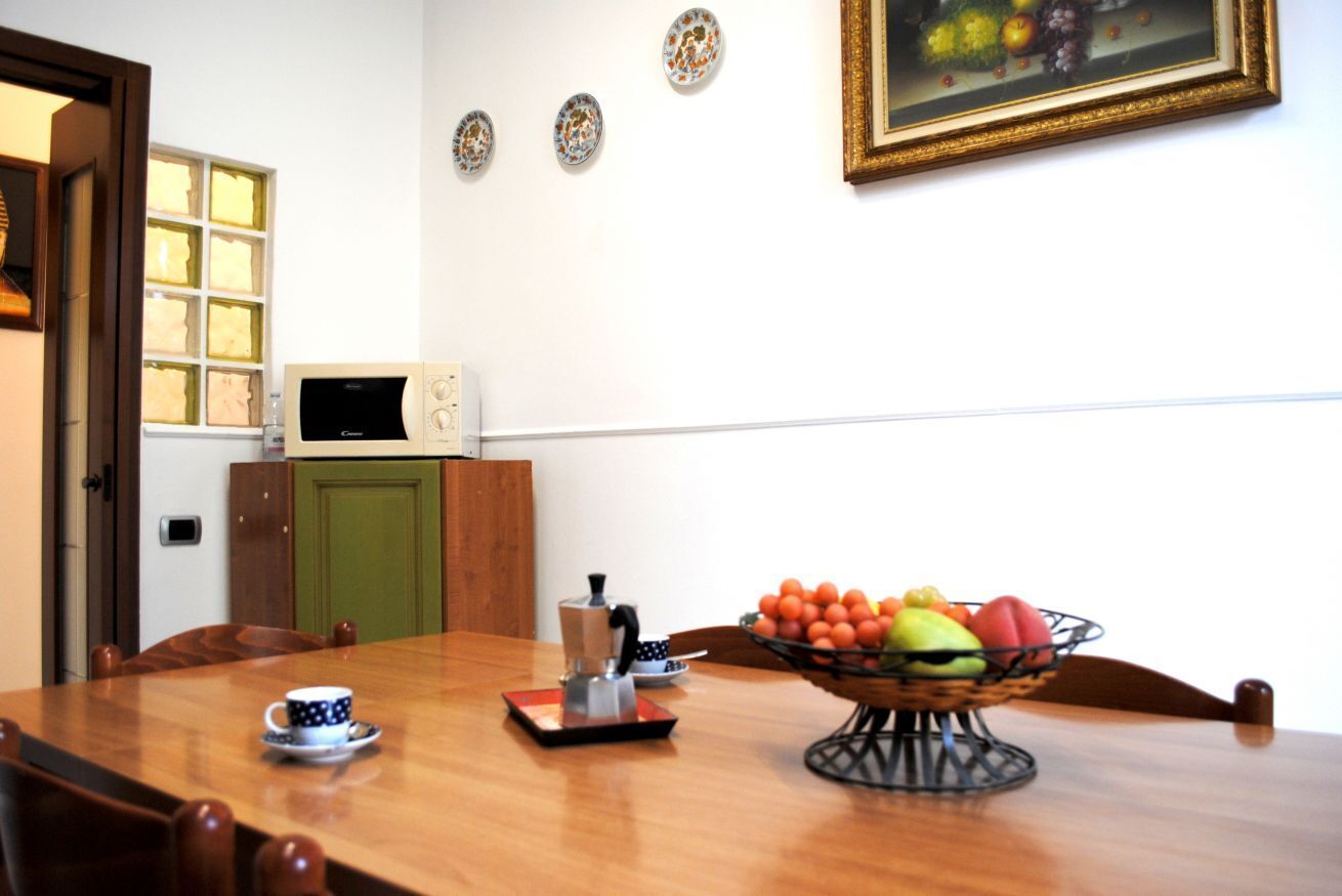 Een vergaderruimte met een houten tafel, stoelen, een koffiezetapparaat, een fruitschaal, een magnetron en een schilderij aan de muur.