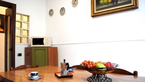 A conference room with a wooden table, chairs, a coffee maker, a bowl of fruit, a microwave, and a painting on the wall. - BNBOOK BORROMEO 1 RHO (RHO)
