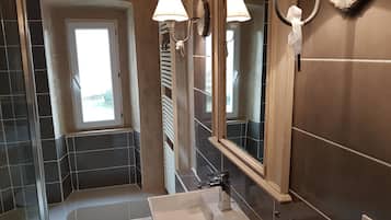 A bathroom with a large mirror, a sink, and two wall-mounted lights.