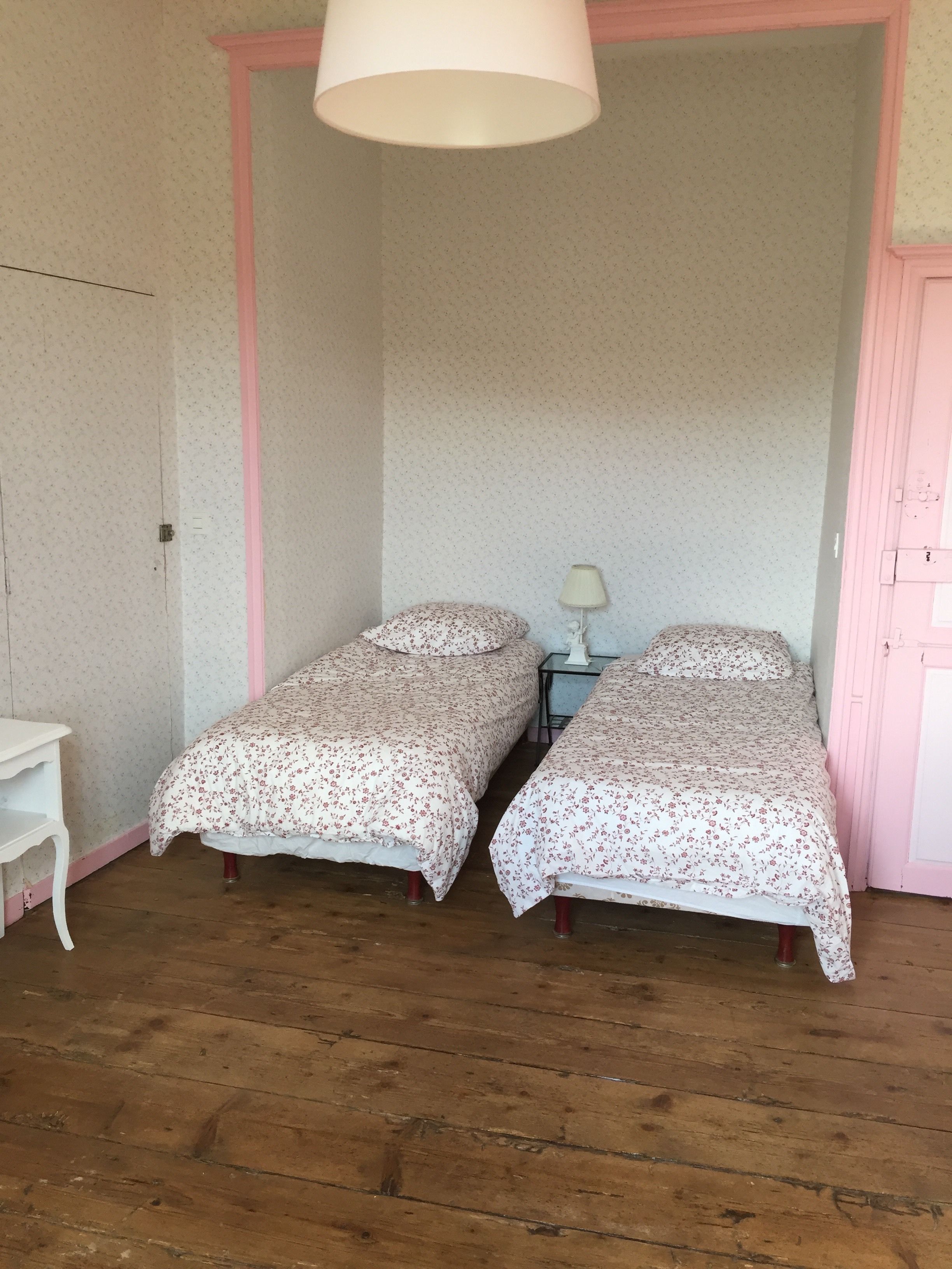 A small room with two single beds, a small table, and a lamp.