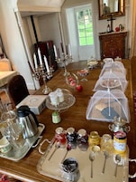 Una mesa de comedor preparada con diversos alimentos, una cafetera y un juego de té.