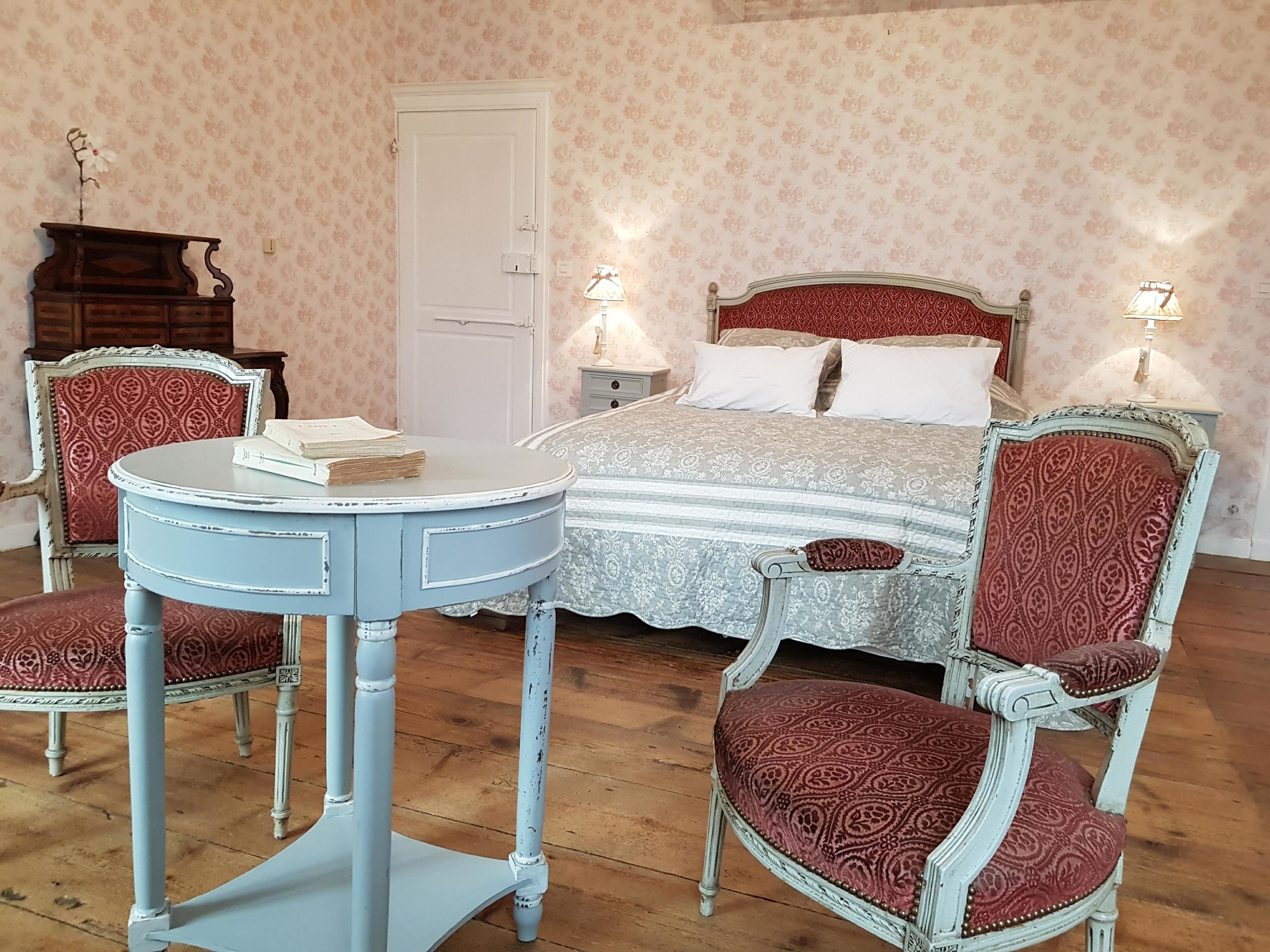 Una camera da letto con un letto, due sedie, un tavolo e una cassettiera.