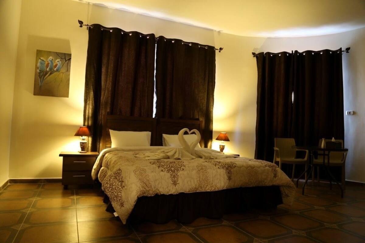 A hotel room with a large bed, two bedside tables with lamps, a chair, and a painting on the wall.