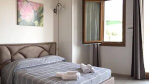 Une chambre à coucher avec un lit, un tableau, une fenêtre avec des rideaux et une porte.