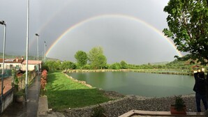 Un paysage paisible avec un étang, un arc-en-ciel et une personne prenant une photo.