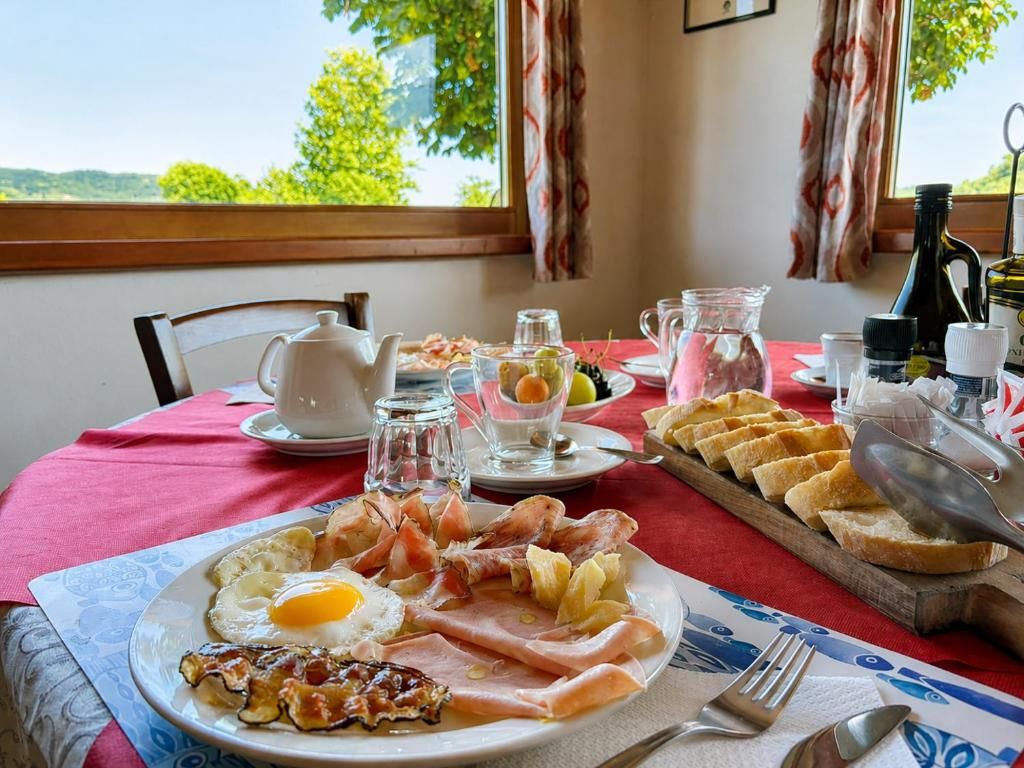 A breakfast table with a plate of eggs, bacon, ham, and toast, a pitcher of water, and a glass of juice.