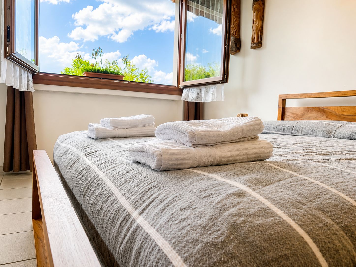 A bedroom with a bed, two windows, and a view of greenery outside.