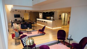 Ein modernes Wohnzimmer mit Barbereich, ausgestattet mit einer Couch, Sesseln und einem Couchtisch.