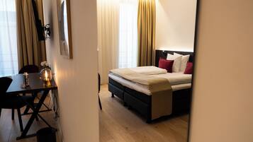 A hotel room with a bed, bedside table, lamp, and curtains.