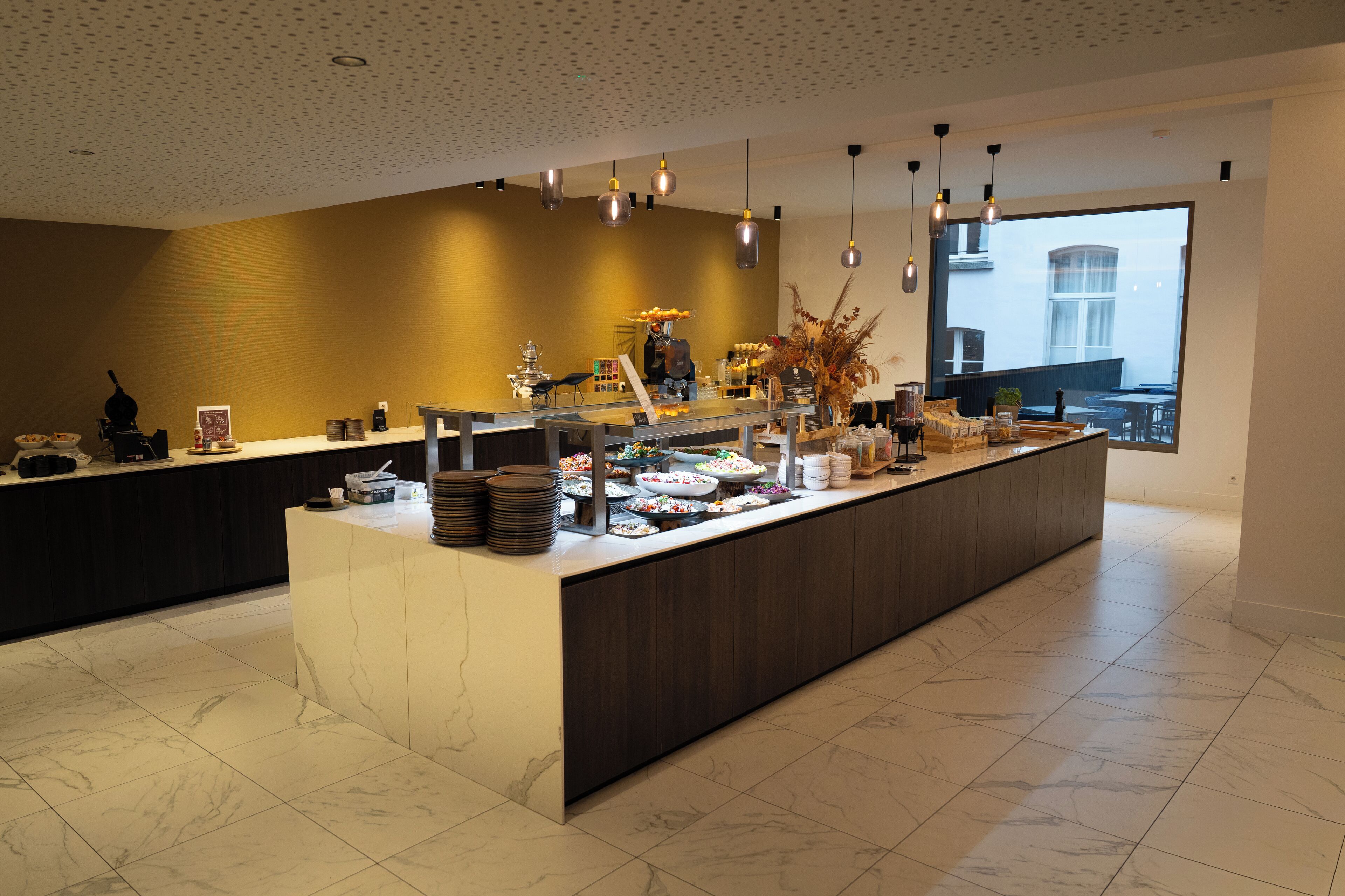 A modern breakfast bar with a variety of food items and a large window providing a view of the outside.