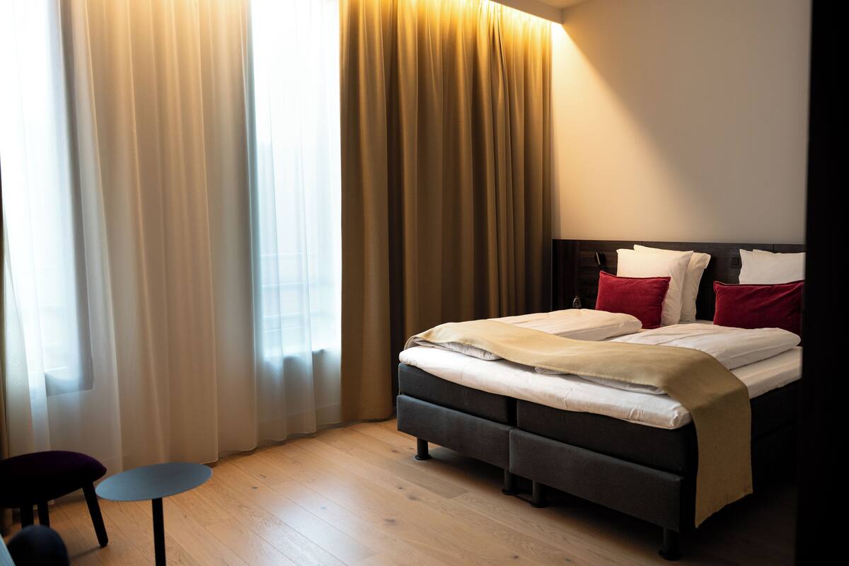 A modern hotel room with a bed, a small table, and a chair.