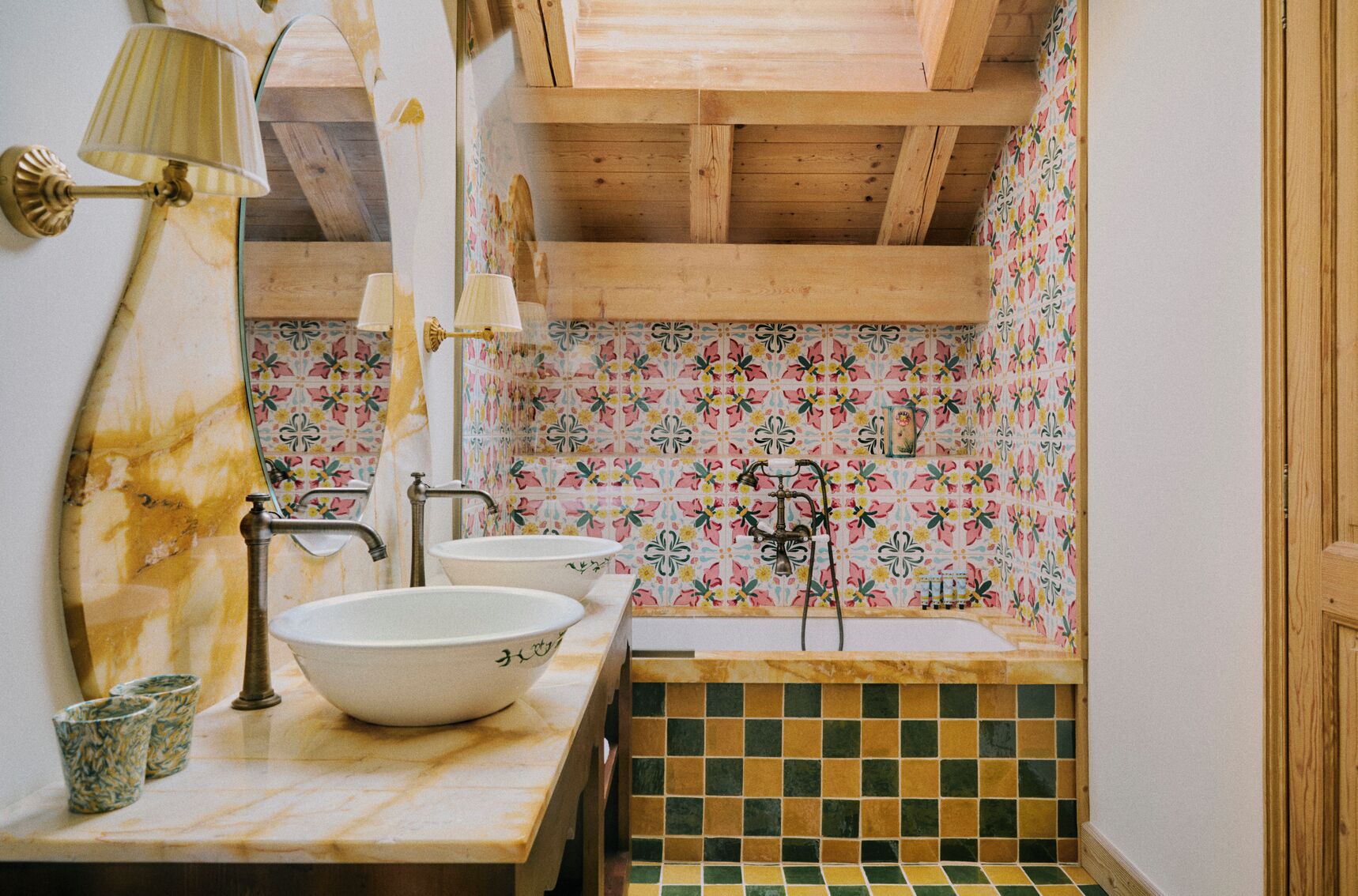 A bathroom with wooden beams, a marble countertop, two sinks, and a tiled shower area.