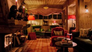 Un cuarto acogedor con chimenea, paredes de madera y un dosel a cuadros sobre la zona de estar.