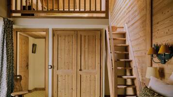A wooden interior with a loft bedroom, a staircase, and a bed with a patterned pillow.