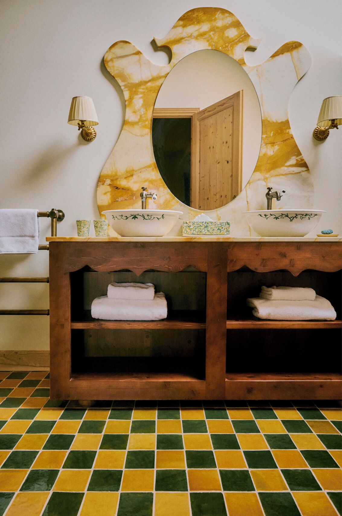 Un baño con tocador de madera, dos lavamanos, un espejo grande y suelo de baldosas.