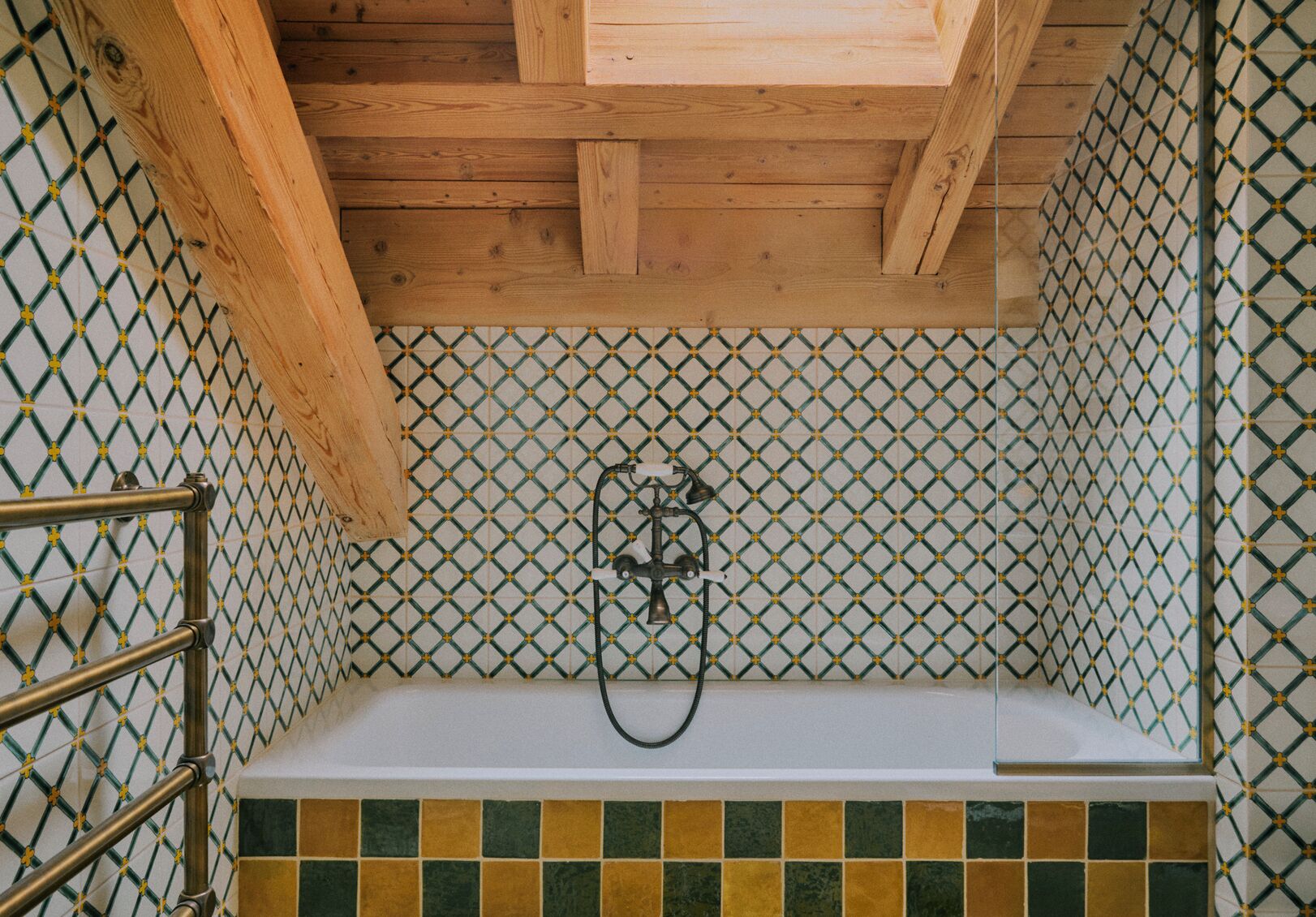 Een badkamer met douche, betegelde wanden en een houten plafond.