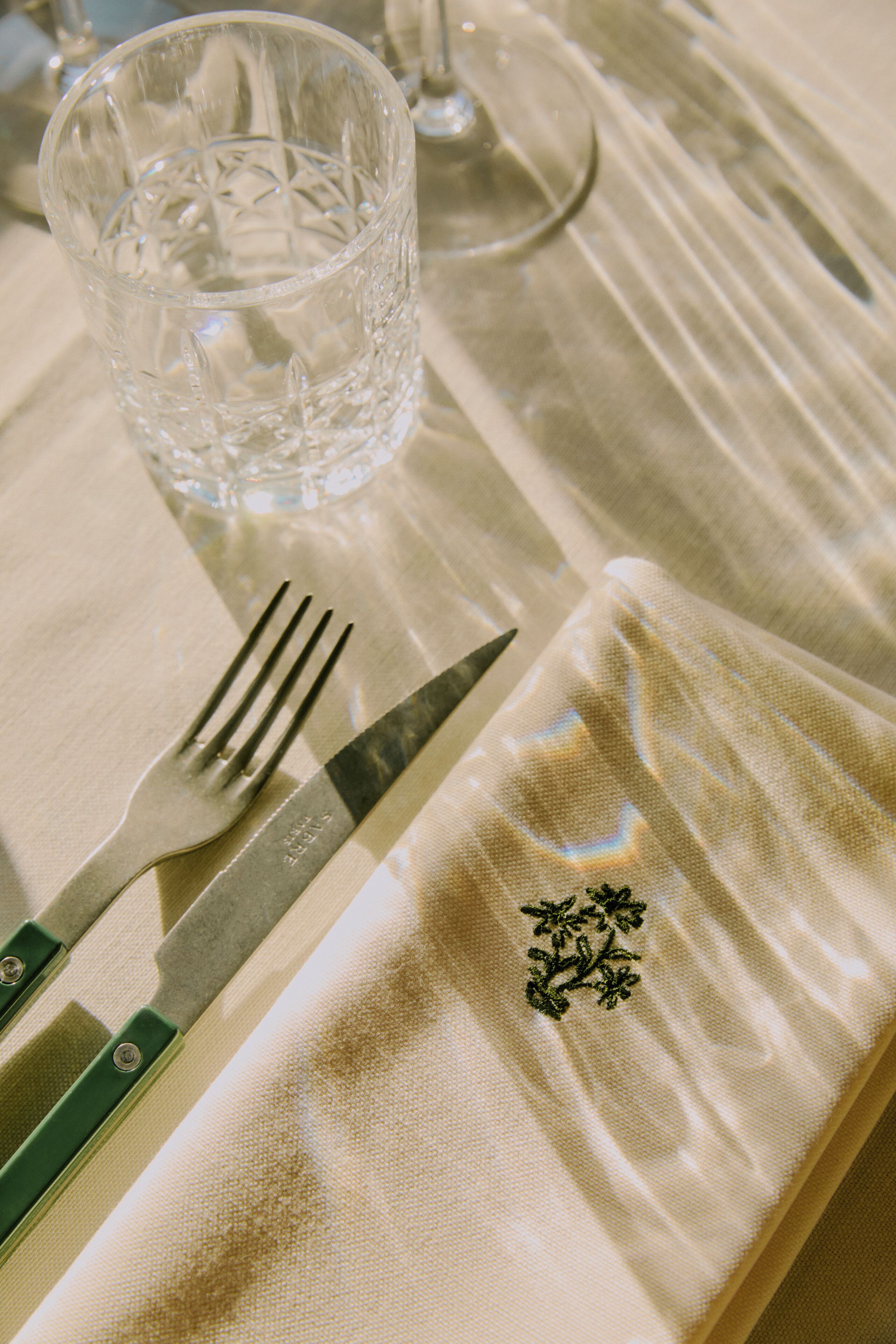 Una mesa servida con tenedor, cuchillo y vaso.