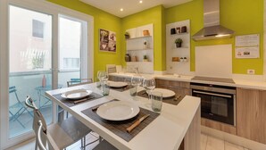 A modern kitchen with a dining area, equipped with a stove, oven, and a large window overlooking a balcony. - 🎖 Le Baulier - 2 bedrooms apartment (Annecy)