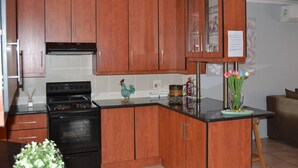 A kitchen with wooden cabinets, a black stove, and a countertop with a vase of flowers. - Africa Emerald at 47 Petronella (Kempton Park)