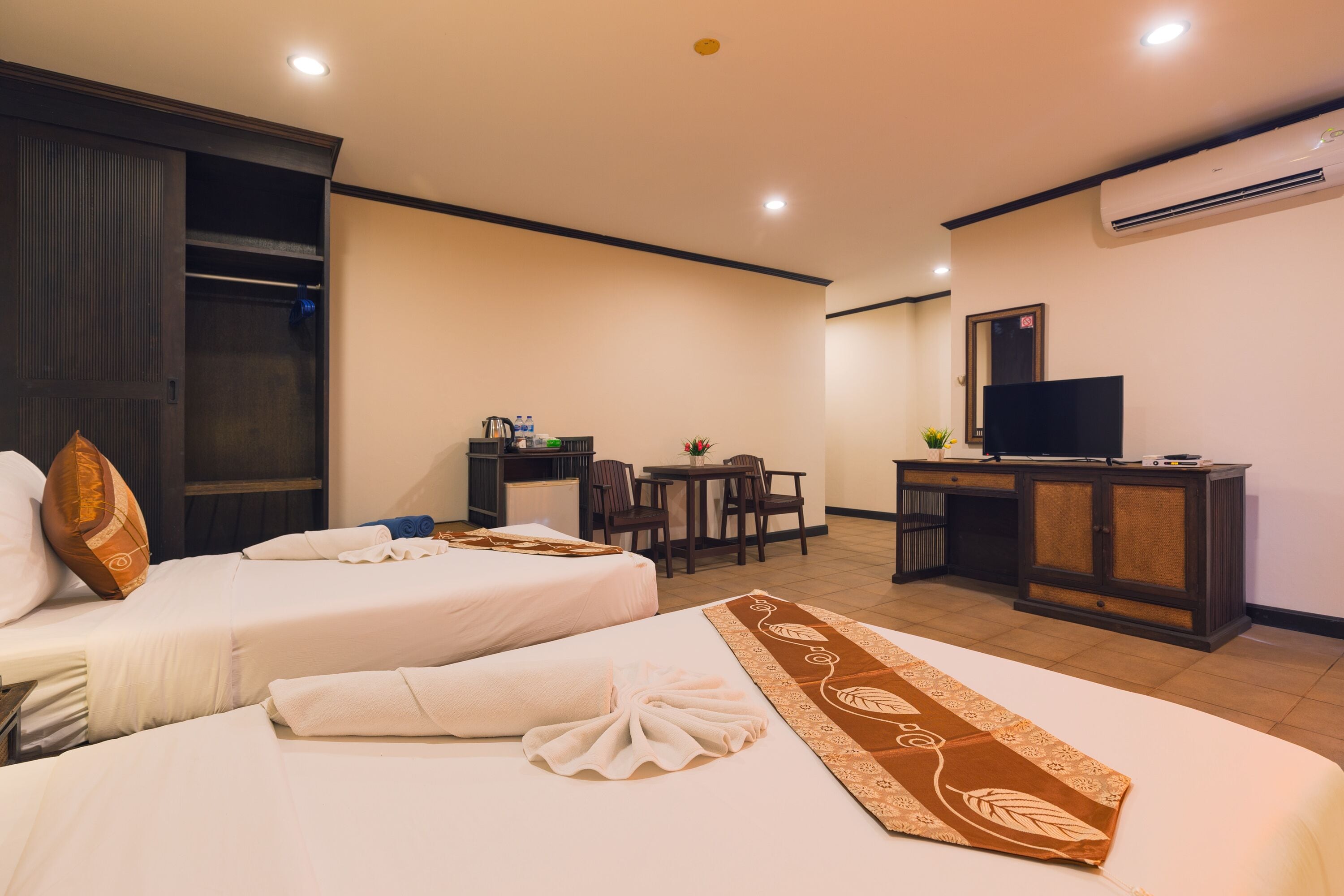 Une chambre d’hôtel avec deux lits, un bureau, une télévision et un coin repas.