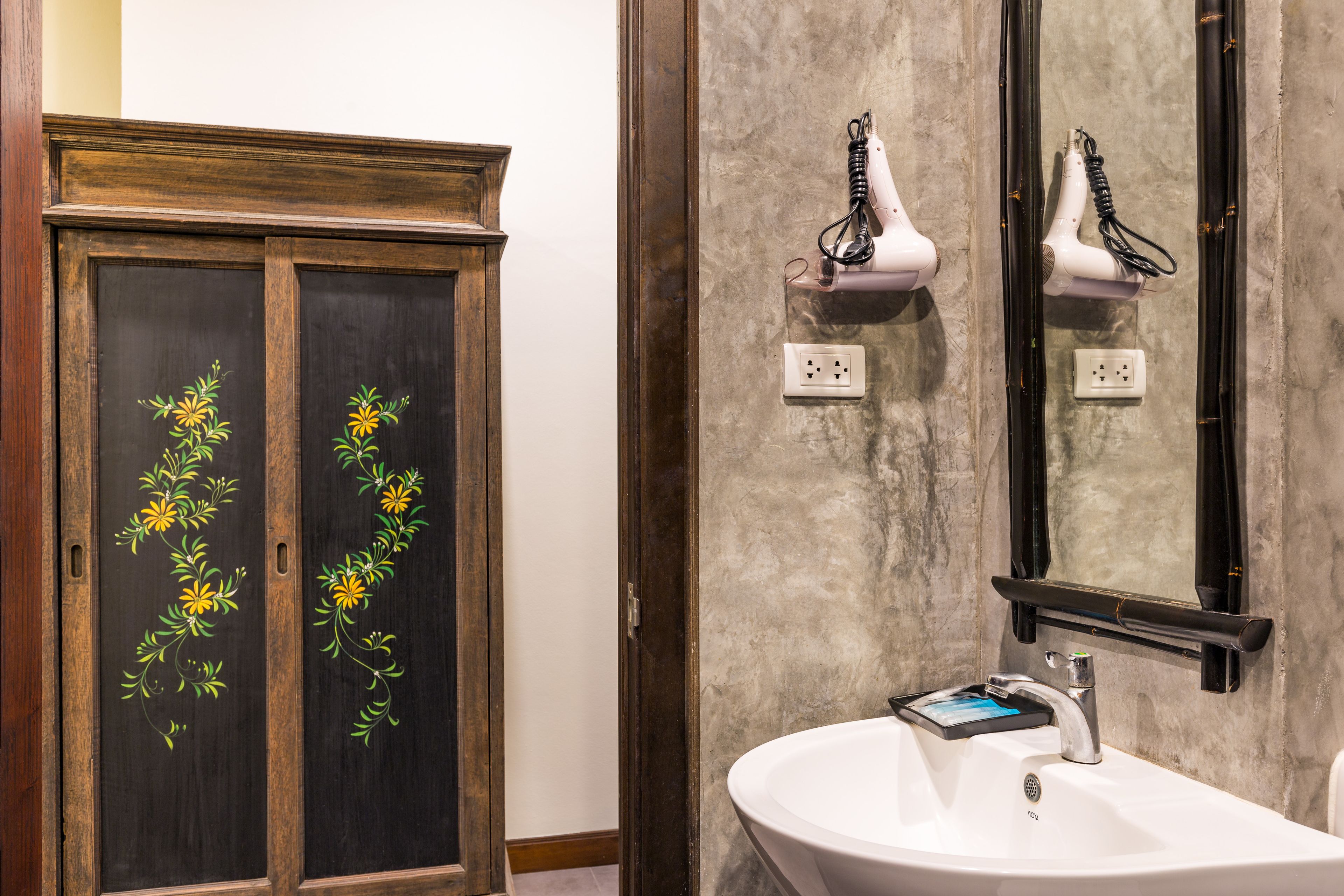 A bathroom with a white sink, a mirror, and two hair dryers mounted on the wall.