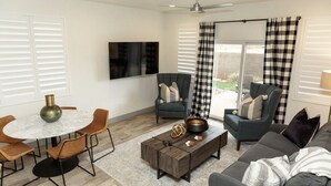 Uma sala de estar moderna com uma mesa redonda, duas poltronas, um sofá e uma mesa de centro.