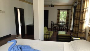 Habitación de hotel con cama, una mesa de comedor con sillas y vistas al exterior por la ventana.