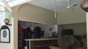 Un área de bar con taburetes, un televisor y un ventilador de techo.