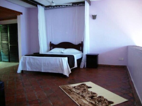 Un dormitorio con cama, mesita de noche y una alfombra estampada.