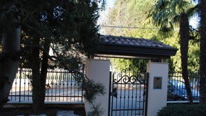 A gated entrance with a metal gate, a stone pathway, and a small covered area with a tiled roof. - BNBOOK-RESIDENZA NAGGI (CASORATE SEMPIONE)