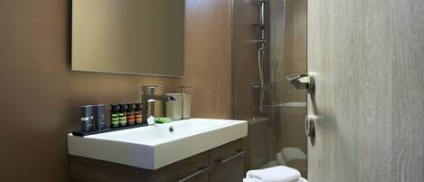 Une salle de bain moderne avec un grand miroir, un lavabo et une douche.