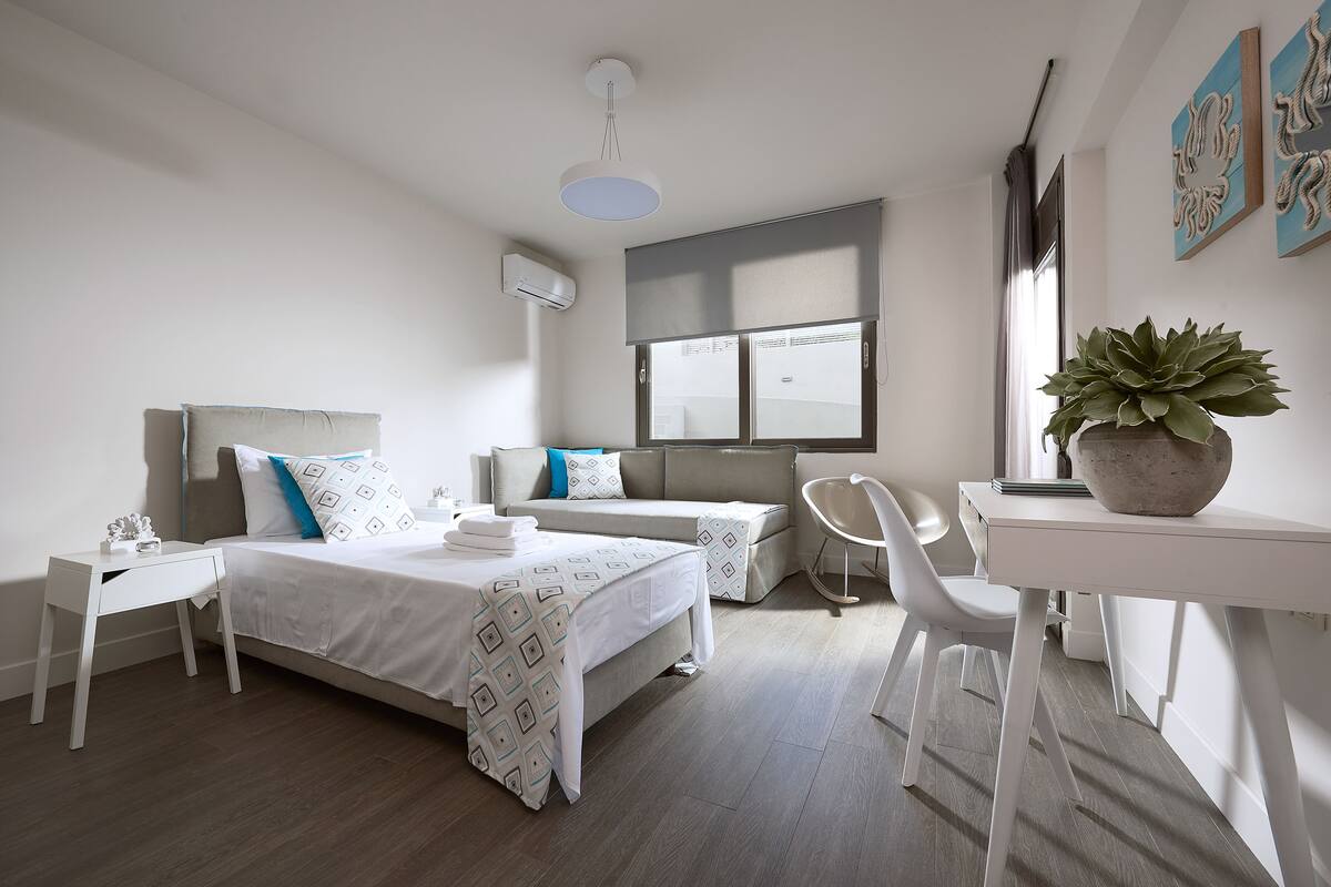 Een moderne hotelkamer met een bed, een bureau, een stoel en een potplant.