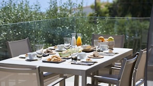 Taula preparada per esmorzar, amb fruita, pastissos i begudes, amb una vista panoràmica.