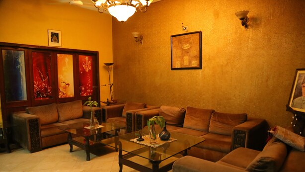 A cozy living room with a sofa set, a glass coffee table, and a chandelier. - Hotel Sweet Inn (Lahore)