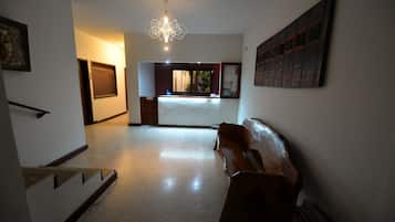 A spacious hallway with a wooden bench, a staircase, and a chandelier.