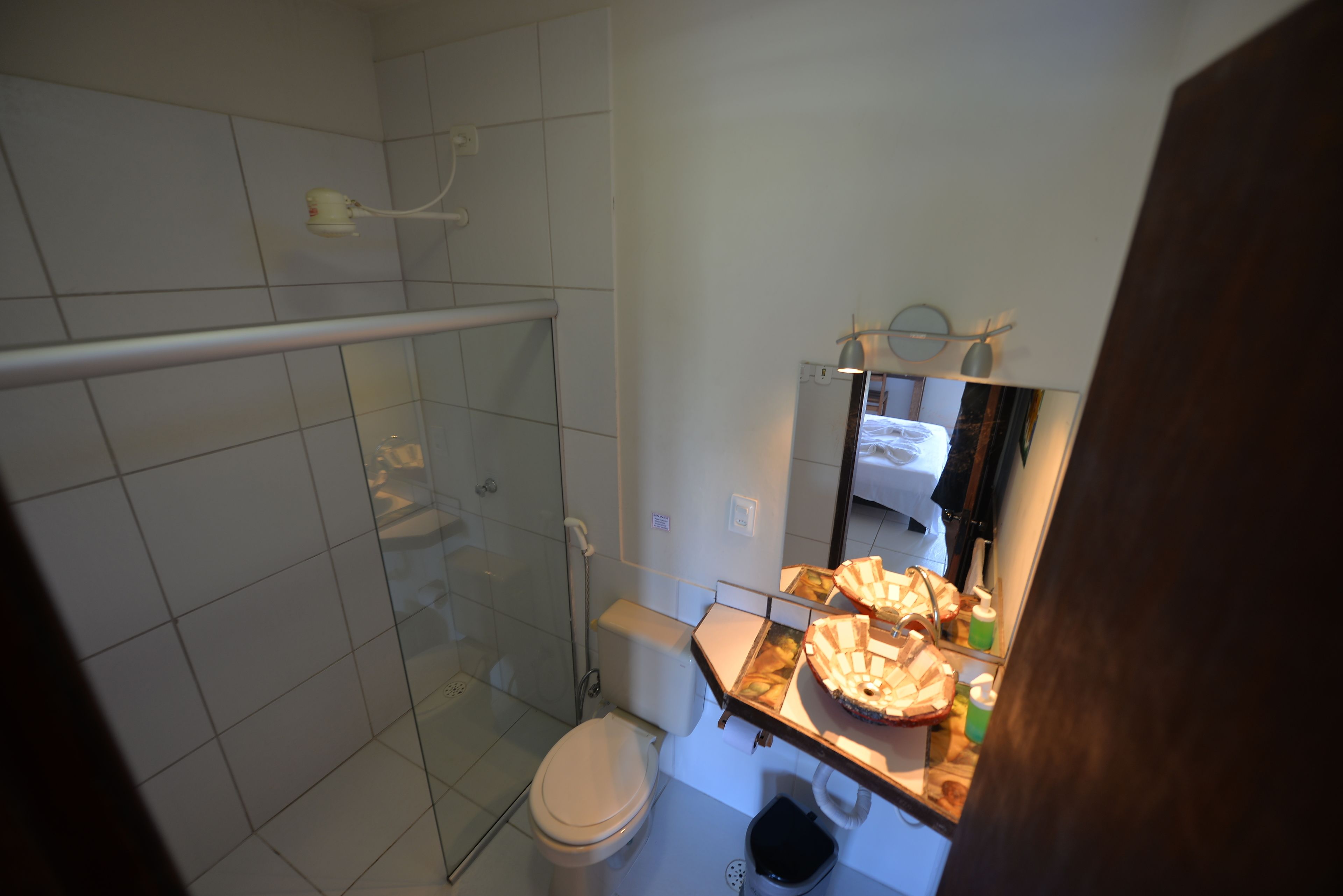 A bathroom with a glass shower enclosure, a toilet, and a sink with a mirror above it.