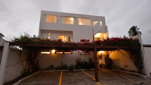 Un bâtiment moderne doté d’une entrée abritée, de plantes en pot et d’une enseigne indiquant qu’il s’agit d’un hôtel.