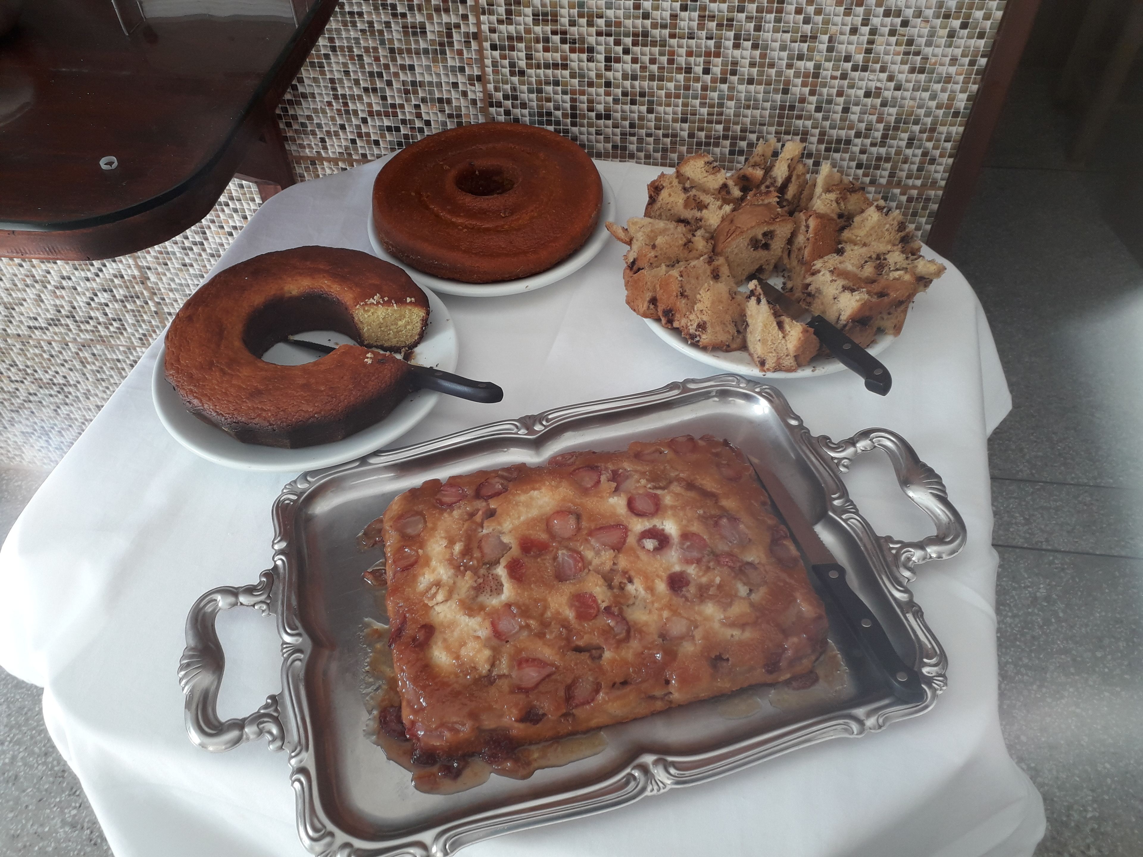 A table with a cake, a loaf of bread, and a tray of breadsticks.
