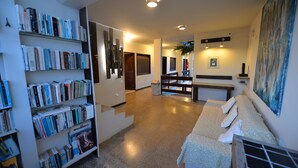 Une pièce spacieuse avec une grande bibliothèque remplie de livres, un canapé confortable avec des coussins et un tableau accroché au mur.