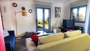 A modern living room with a sofa, a television, and a dining area. - Villa Constandinos (Hersonissos)