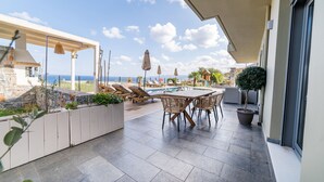 A terrace with a pool, lounge chairs, and a table. - Villa Constandinos (Hersonissos)