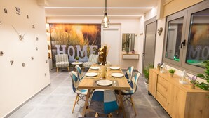 A modern dining area with a wooden table set for four, surrounded by patterned chairs. - Villa Constandinos (Hersonissos)