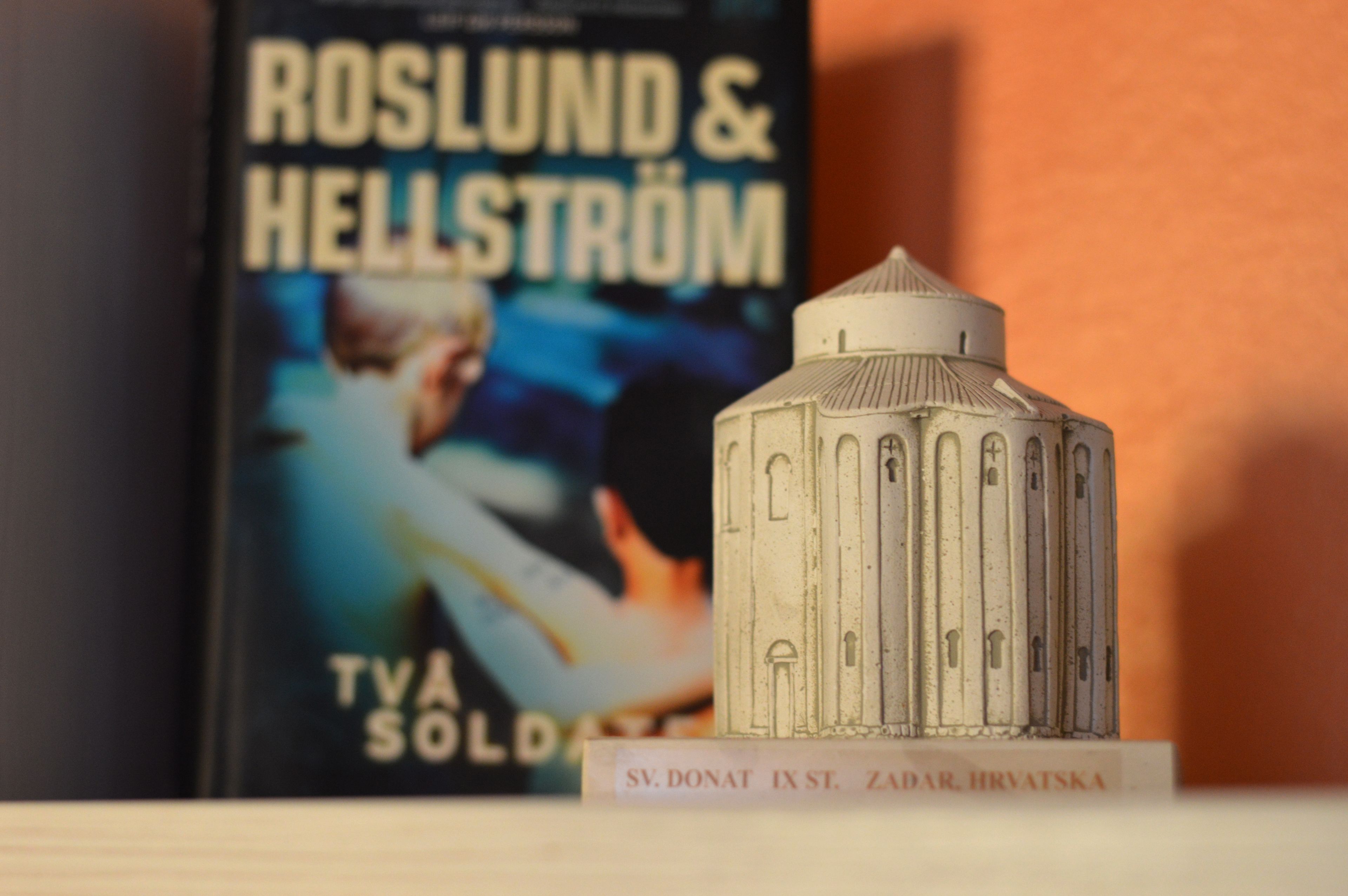 A model of a building with a domed roof and vertical lines, placed in front of a book titled "ROSLUND & HELLSTROM" by T.V. SÖLDAL.