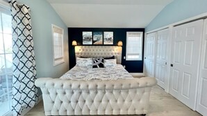 Un dormitorio con cabecera capitonada, una cama grande y vistas al exterior.