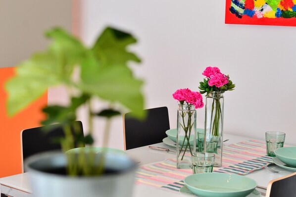 Enjoy meals in a stylish dining area with a table set for two, surrounded by vibrant artwork and lush greenery.