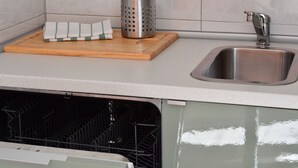 Una cocina con un lavamanos de acero inoxidable, una tabla de cortar de madera y un rallador.