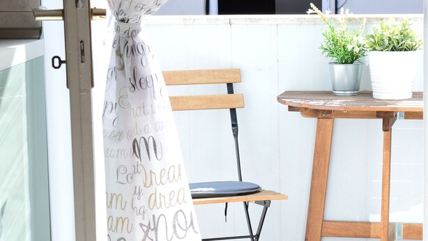 Una silla y una mesa de madera en un balcón con una planta en maceta.