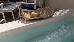 A clear swimming pool with a wicker basket and a blue cushion on the edge.